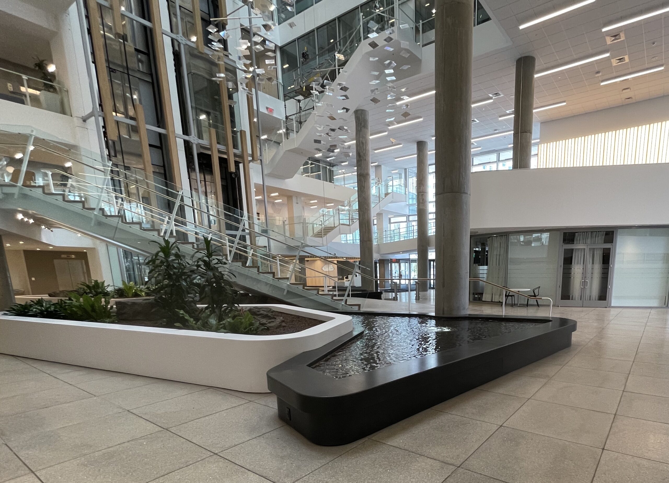 Free-form-stream-water-feature-pool-in-ten-story-atrium-left-of-stairs-takeda-cambridge-ma-by-water-structures