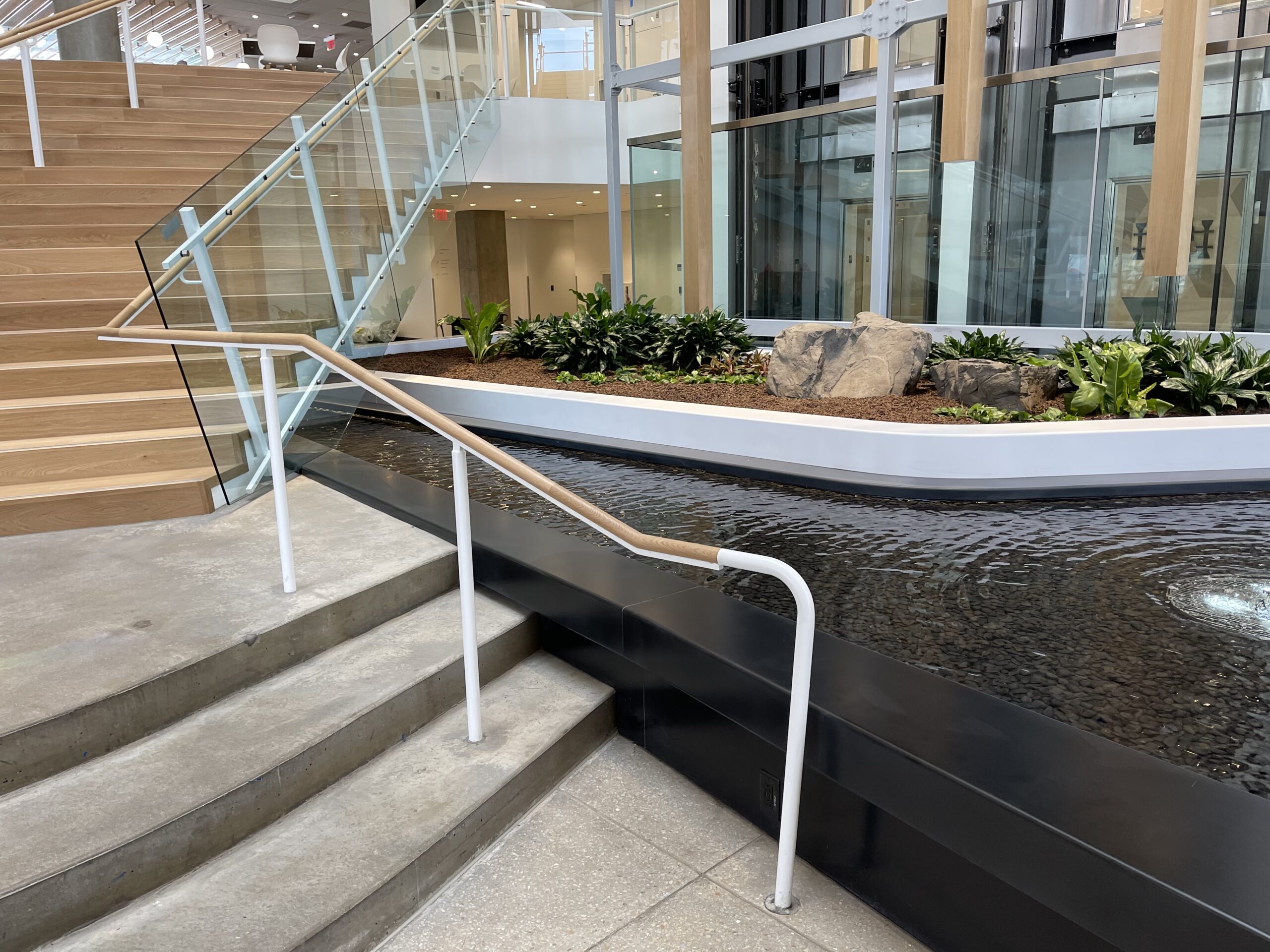 Free-form-stream-water-feature-pool-in-ten-story-atrium-under-stairs-runnel-takeda-cambridge-ma-by-water-structures